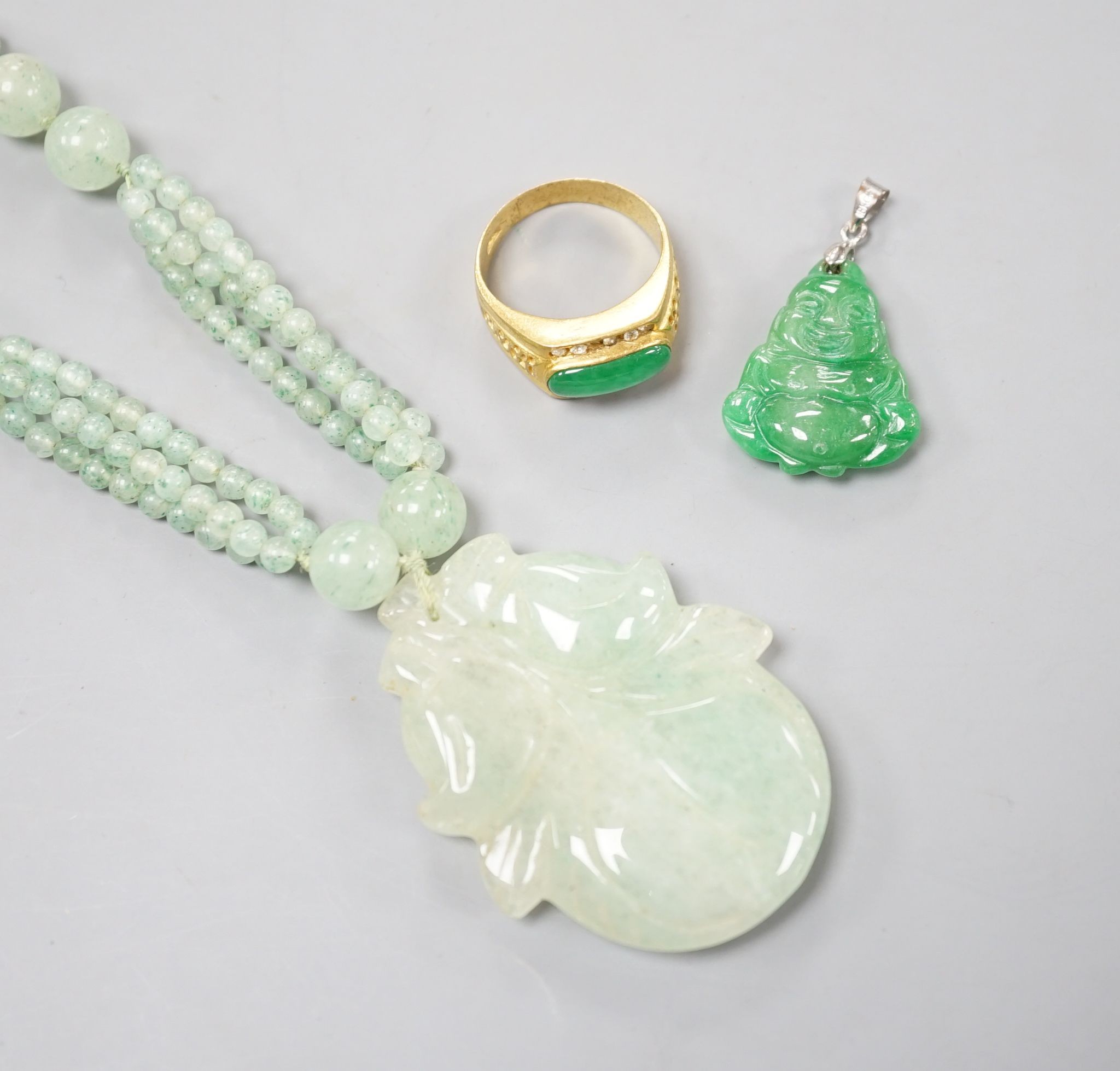 A carved jade pendant, 53mm on a quartz bead necklace, one other jade pendant and a jade, paste and gilt metal ring.